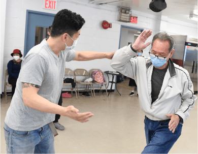 Instructor demonstrating a protection technique to older adult in a self-defense class