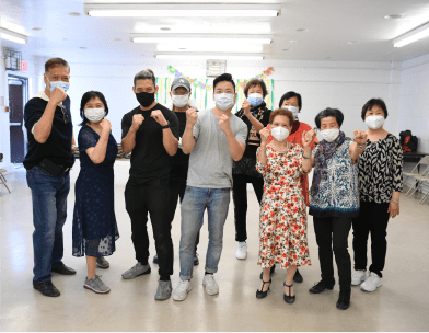 Group of older Asian adults and instructors posing with boxing fists